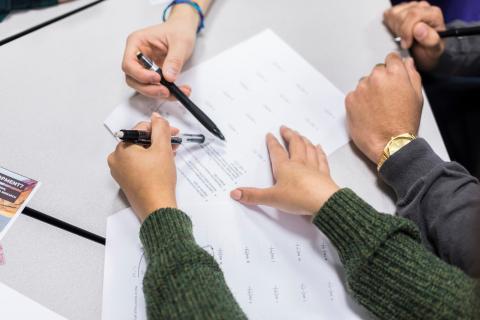 Three sets of hands collaboration over documents.