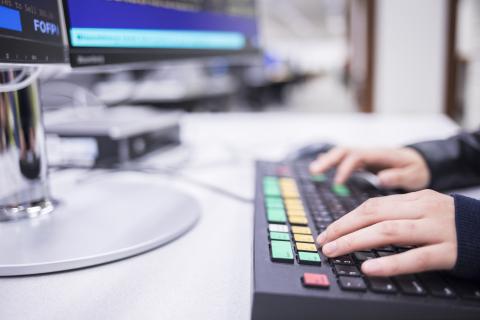 A set of hands typing at a computer keyboard.