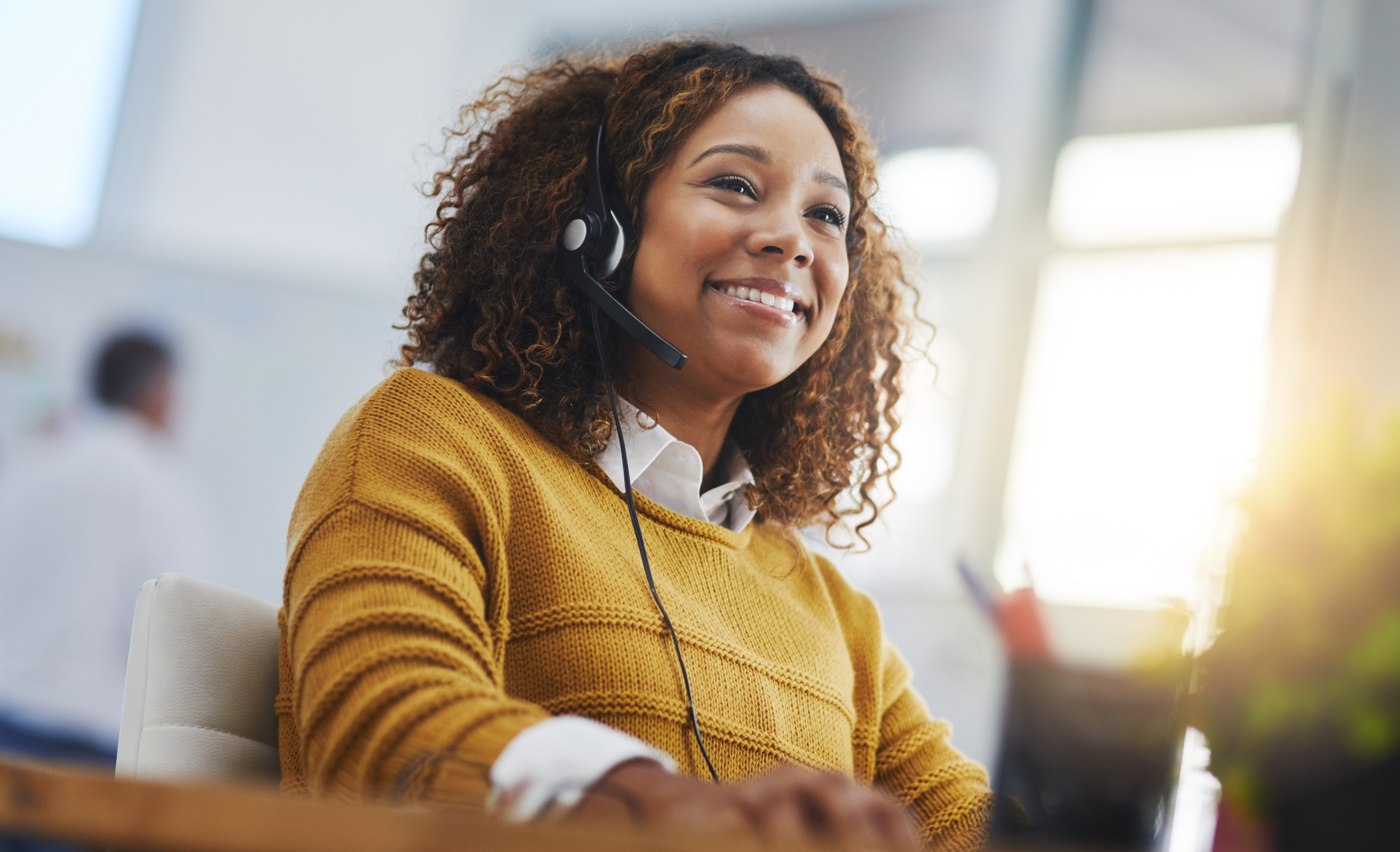 Smiling African American woman call center agent with voip headset taking a call.