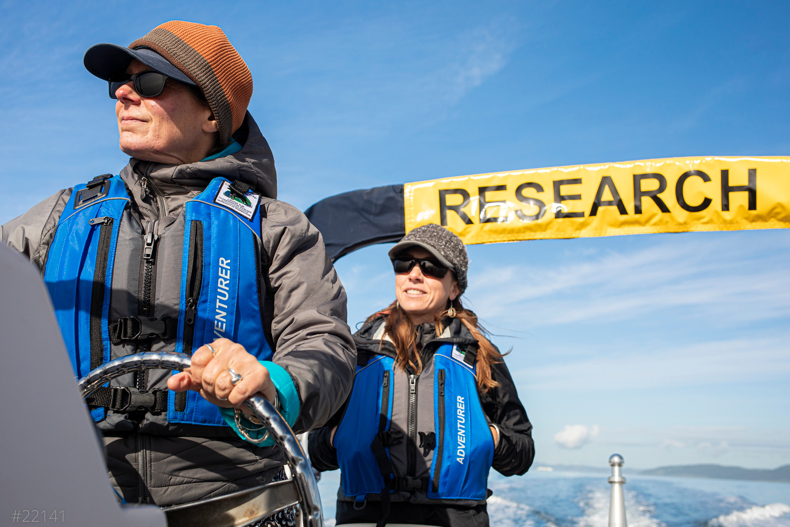 Two women on a boat with a large sign labeled "RESEARCH"