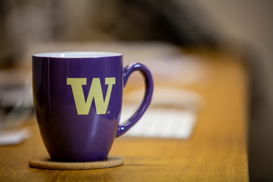 purple mug with gold W logo sitting on a desk