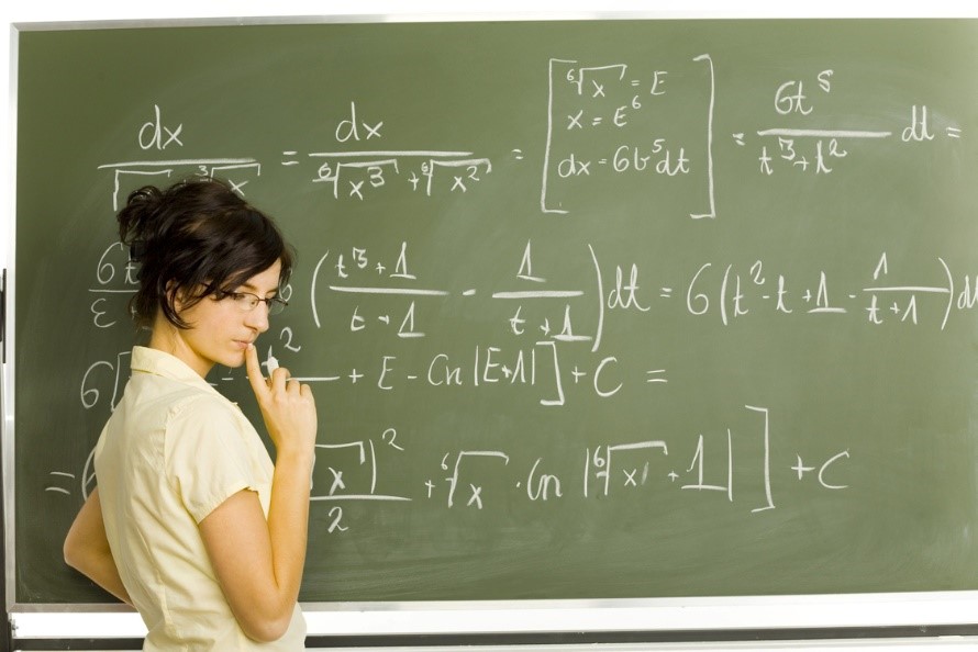 Woman looking lost in thought at a chalk board