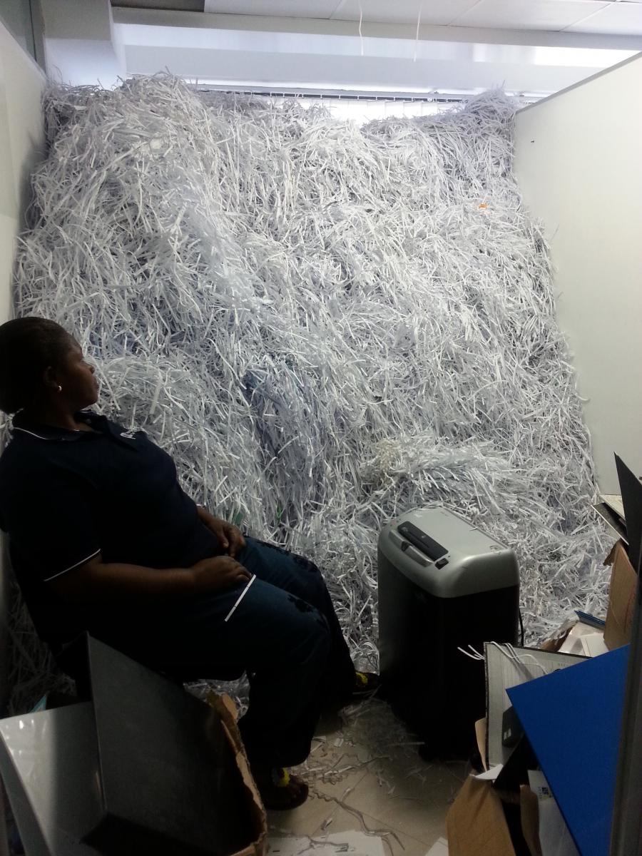 Black woman worker sitting in an office room full of shredded paper