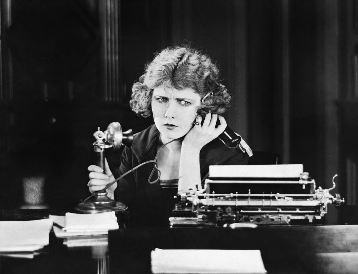 alarmed 1930s woman on phone in office