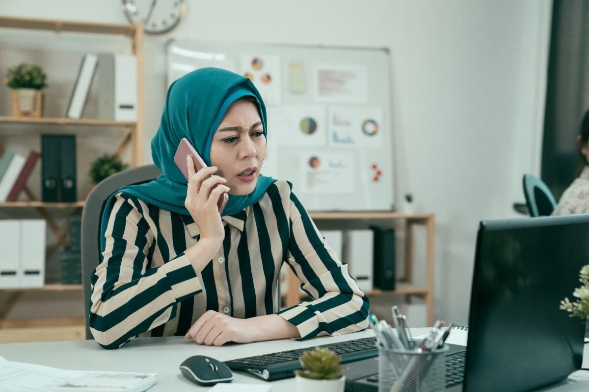 frustrated woman in hijab on phone in office